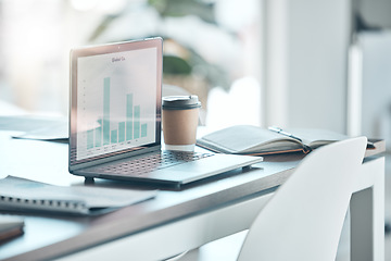 Image showing Empty workplace with laptop, notebook and coffee on a desk in a modern creative office space. Corporate document of graphs, data and charts on the computer for a business meeting or discussion.