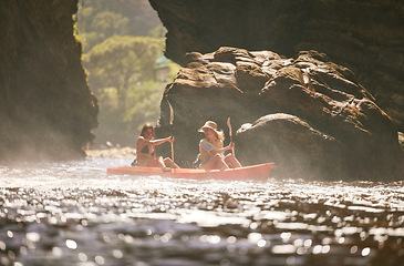 Image showing Travel, kayak and female friends on a vacation adventure while on an river or sea with a mountain view in nature. Women having fun while traveling and enjoying canoeing boat activity on holiday trip