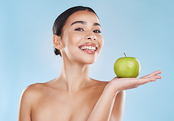 Image showing Health, food and apple diet with happy woman holding fruit against blue background. Portrait of a young female excited by weight loss and nutrition, showing benefits of healthy, balance lifestyle