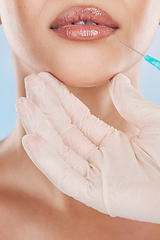 Image showing Needle, surgery and lips with a woman getting an injection in her mouth for beauty, skincare and medicine in studio on a blue background. Filler, product and cosmetics with a young female model inside