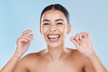 Image showing Beauty, teeth and skincare of a woman in dental floss isolated against a blue studio background. Portrait of attractive female flossing for healthy mouth care, tooth and gum hygiene with a big smile.