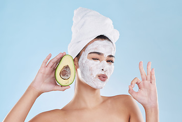 Image showing Face mask, avocado and woman with a ok sign with health, wellness and organic lifestyle in studio. Girl doing fresh, clean and natural selfcare routine while holding fruit for nutrition and diet.