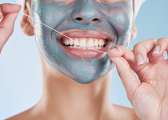 Image showing Dental, face mask and woman flossing her teeth for healthy and strong teeth in a studio portrait with a blue background. Girl cleaning her mouth, face and skin with beauty self care and oral hygiene