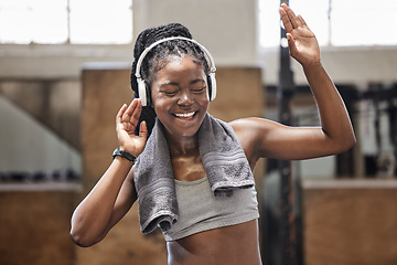 Image showing Happy athlete singing and dance with headphone in a gym after fitness, exercise and training. Cheerful woman sweating having fun with music after health and wellness cardio workout in a sports club