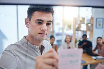 Image showing Business man writing on sticky note in meeting, doing creative advertising presentation on glass board in workshop and training employees in work office. Corporate worker planning on post it paper