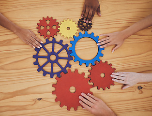 Image showing Hands, gears and collaboration with a team of people working with cogs and equipment on a table in the office. Teamwork, synergy and planning with a business group meeting to talk company strategy