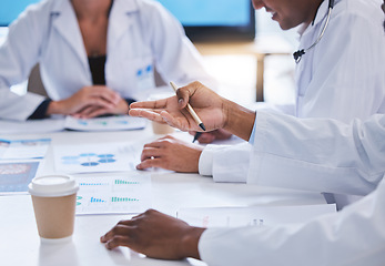 Image showing Team of doctors consulting in meeting with paperwork of graphs, data and charts in hospital conference. Healthcare staff discussing health statistics, results and strategy in medical clinic office.