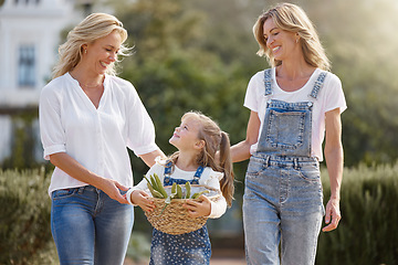 Image showing Lesbian couple on an outdoor walk with their child for fresh air in a garden during spring. Happy lgbtq women bonding with their girl kid while having fun in nature after harvesting crops together.