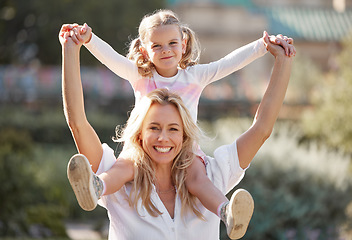 Image showing Happy mother playing with daughter on her shoulders in their backyard on a sunny day. Energetic woman play and having fun with her girl. Family bonding and laughing together on the weekend