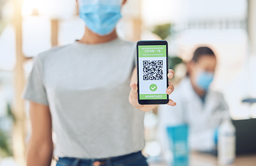 Image showing QR code for covid vaccine passport and certificate at covid 19 vaccination center or site for health and safety verification. Hands of young girl with smartphone for approval or confirmation document