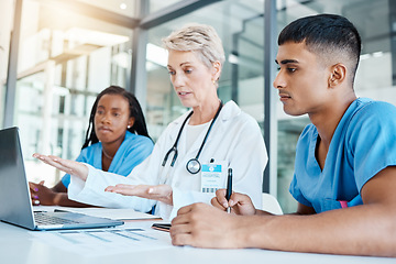 Image showing Doctor teaching medical students on laptop in an office at the hospital while writing notes. Experienced professor with stethoscope training healthcare workers. Surgeons analyzing results on computer