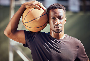 Image showing Portrait african american man standing with a basketball on the court. Fitness male athlete or player holding a sports ball after playing, training and practice game in the background on a court