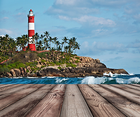 Image showing Wood planks floor with old lighthouse and waves of sea