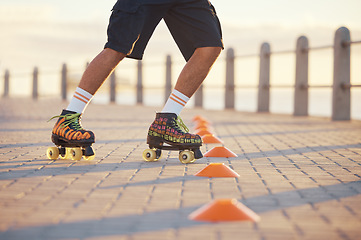 Image showing Roller skates, sport and feet with a man riding around cones for training, fitness and exercise on the promenade by the beach. Male athlete roller skating outside for sports, health and recreation