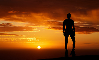 Image showing Sunset, silhouette and woman admiring the horizon view and watching the sun and orange or red sky while enjoying freedom, relax and mindfulness. Travel, scenery and beauty of nature by the sea