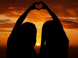 Image showing Love, freedom and heart sign by couple silhouette of lesbian and lgbt pride, hand shape at sunset. Women celebrate relationship, free, in love and proud. Females celebrating their bond and status
