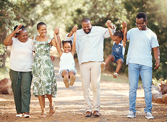 Image showing Happy black family bonding and having fun at a park together, laughing and playful holding hands on active walk in nature. African American children enjoy time outdoors with parents and grandparents