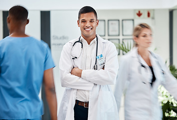 Image showing Happy, medical and doctor in hospital with smile and confident, arms crossed in busy hallway. Male, surgeon and healthcare specialist physician in hospital. Staff, clinical internship.