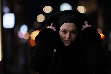 Image showing Muslim woman walking on urban city street on a cold winter night wearing hijab