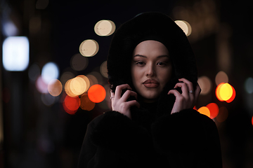 Image showing Muslim woman walking on urban city street on a cold winter night wearing hijab