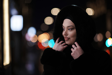 Image showing Muslim woman walking on urban city street on a cold winter night wearing hijab