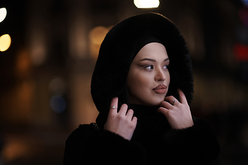 Image showing Muslim woman walking on urban city street on a cold winter night wearing hijab