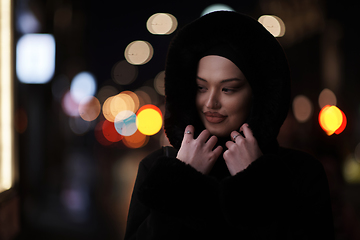 Image showing Muslim woman walking on urban city street on a cold winter night wearing hijab