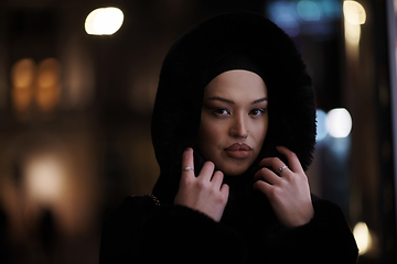 Image showing Muslim woman walking on urban city street on a cold winter night wearing hijab