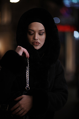 Image showing Muslim woman walking on urban city street on a cold winter night wearing hijab