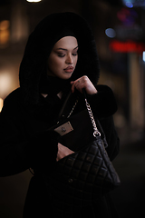 Image showing Muslim woman walking on urban city street on a cold winter night wearing hijab