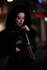 Image showing Muslim woman walking on urban city street on a cold winter night wearing hijab