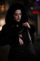 Image showing Muslim woman walking on urban city street on a cold winter night wearing hijab