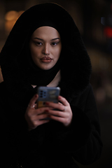 Image showing Muslim woman walking on urban city street on a cold winter night wearing hijab