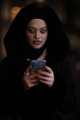 Image showing Muslim woman walking on urban city street on a cold winter night wearing hijab