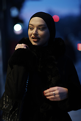 Image showing Muslim woman walking on an urban city street on a cold winter night wearing hijab