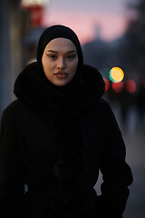 Image showing Muslim woman walking on an urban city street on a cold winter night wearing hijab