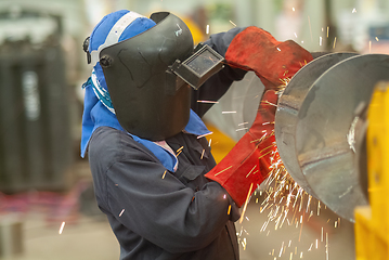 Image showing Worker using an angle grinder, making a screw conveyor