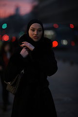 Image showing Muslim woman walking on an urban city street on a cold winter night wearing hijab