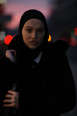 Image showing Muslim woman walking on an urban city street on a cold winter night wearing hijab