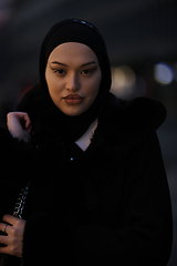 Image showing Muslim woman walking on an urban city street on a cold winter night wearing hijab