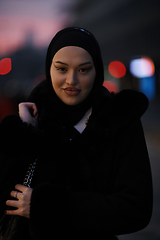 Image showing Muslim woman walking on an urban city street on a cold winter night wearing hijab