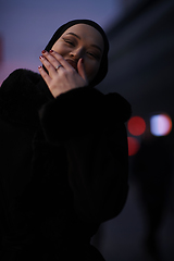 Image showing Muslim woman walking on an urban city street on a cold winter night wearing hijab