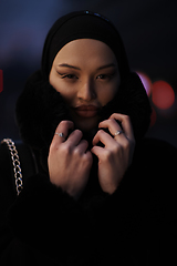 Image showing Muslim woman walking on an urban city street on a cold winter night wearing hijab