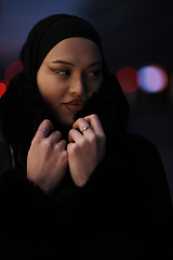 Image showing Muslim woman walking on an urban city street on a cold winter night wearing hijab