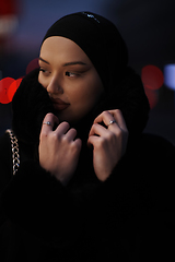 Image showing Muslim woman walking on an urban city street on a cold winter night wearing hijab