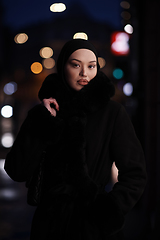 Image showing Muslim woman walking on an urban city street on a cold winter night wearing hijab