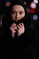 Image showing Muslim woman walking on an urban city street on a cold winter night wearing hijab