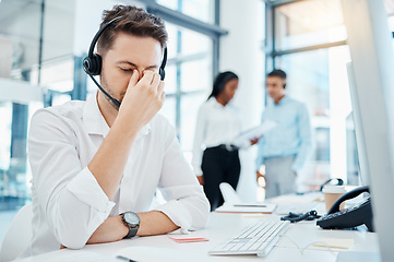 Image showing Call center, headache and burnout of a man in customer service or support with eye strain at the office. Business male or employee in telemarketing suffering from head pain at the company workplace.