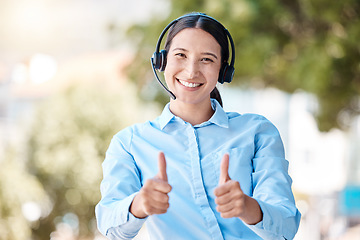 Image showing Thumbs up, customer service and happy woman standing outside with a headset and a positive and friendly attitude. Portrait of CRM, telemarketing and call center operator showing support and thank you