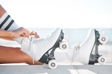 Image showing Closeup of roller skate shoes on the floor outdoor on the promenade at the beach during spring. Person putting on skating boots to do a fun sports activity for exercise in nature at the ocean.